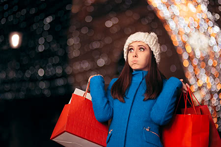 a woman looks slightly overwhelmed while doing her holiday shopping