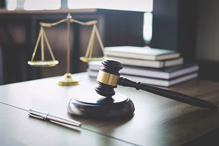 a gavel and hanging scale sit on the desk in a courtroom